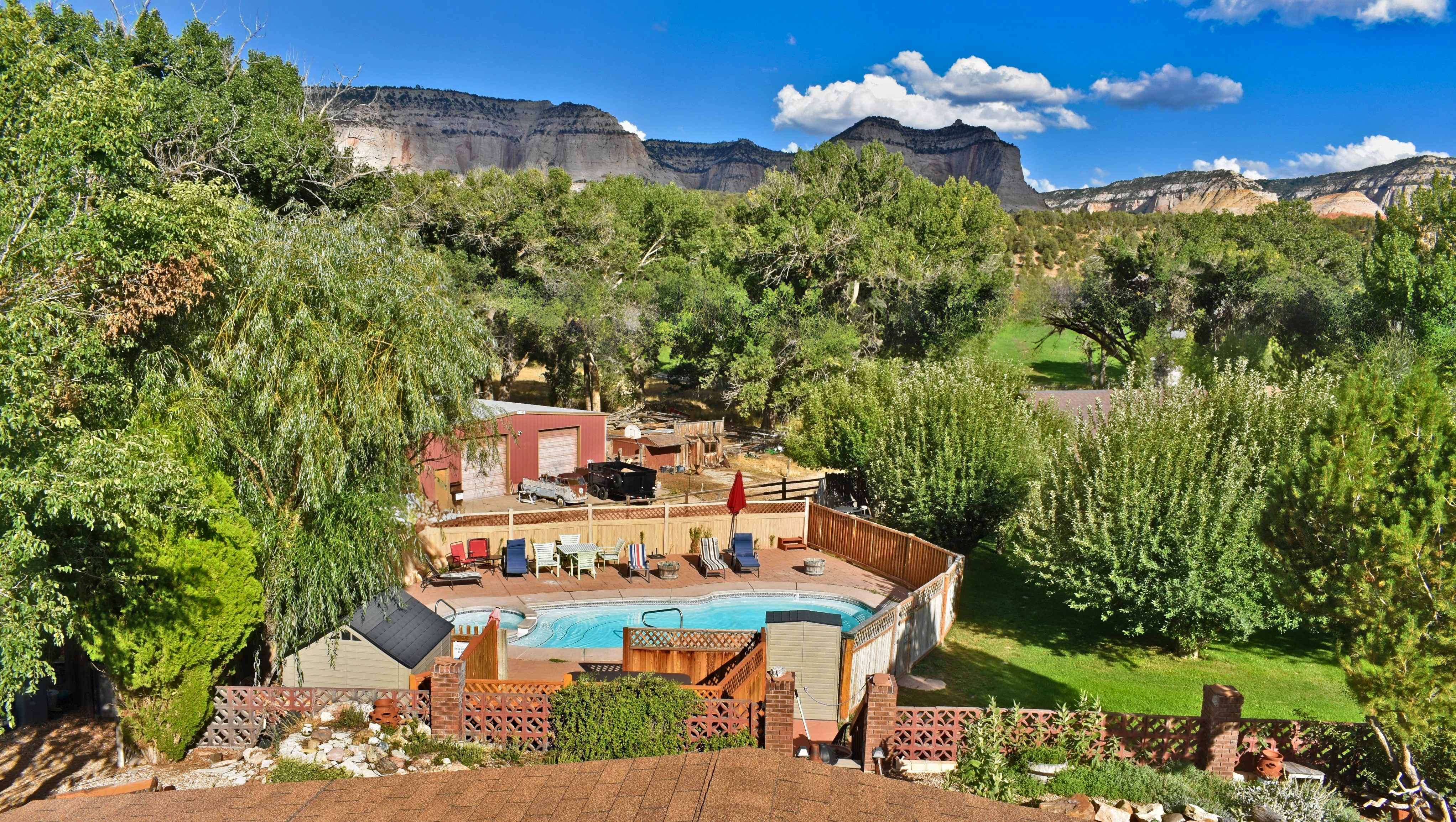 A hotel pool area surrounded by trees and a mountain view.